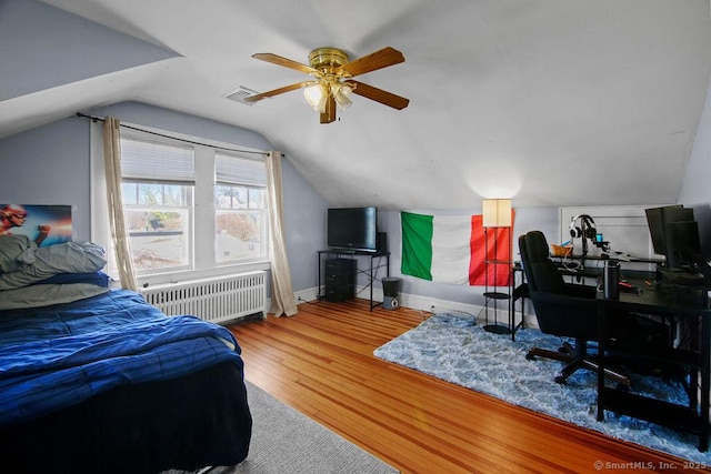 bedroom featuring lofted ceiling, visible vents, radiator heating unit, wood finished floors, and baseboards