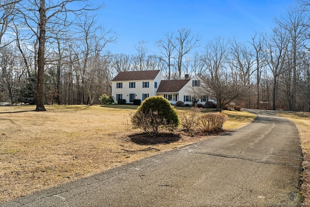 view of front of home with a front lawn, aphalt driveway, and a chimney