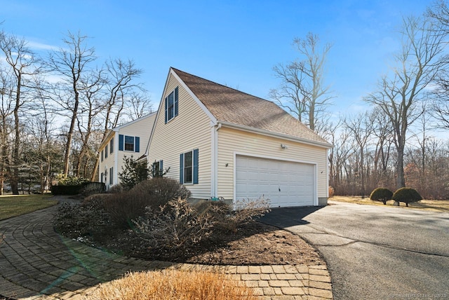 view of property exterior with a garage, driveway, and roof with shingles