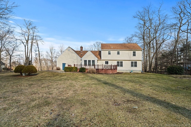 rear view of house featuring a wooden deck, a lawn, and a chimney