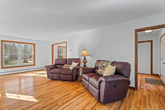 living room featuring light wood-type flooring, a baseboard radiator, plenty of natural light, and baseboards