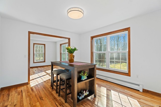 dining room featuring a wealth of natural light, wood finished floors, baseboards, and baseboard heating