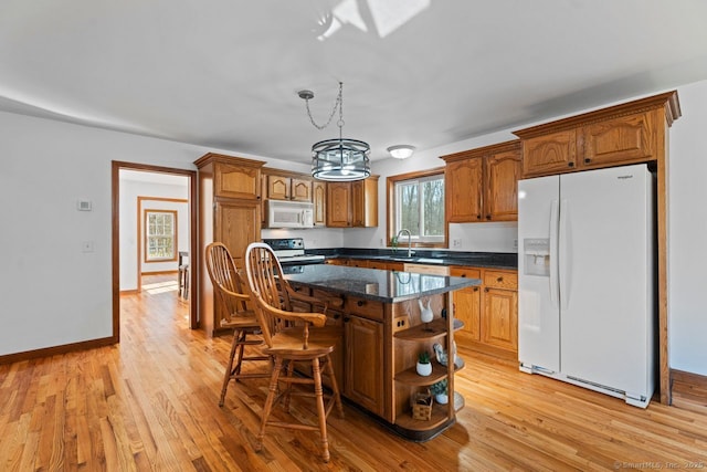 kitchen featuring light wood finished floors, a sink, white appliances, and open shelves