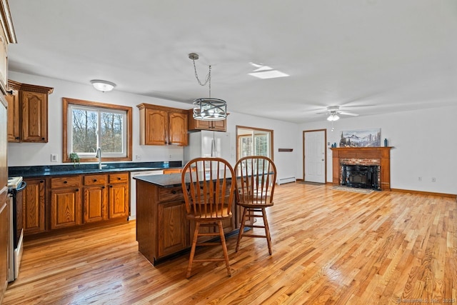 kitchen with electric range, a fireplace with flush hearth, dark countertops, freestanding refrigerator, and light wood-style floors