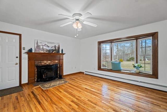 unfurnished living room with light wood-type flooring, a baseboard radiator, baseboards, and a fireplace