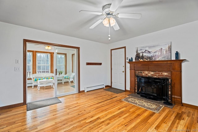 living area featuring baseboard heating, ceiling fan, baseboards, and light wood-style floors