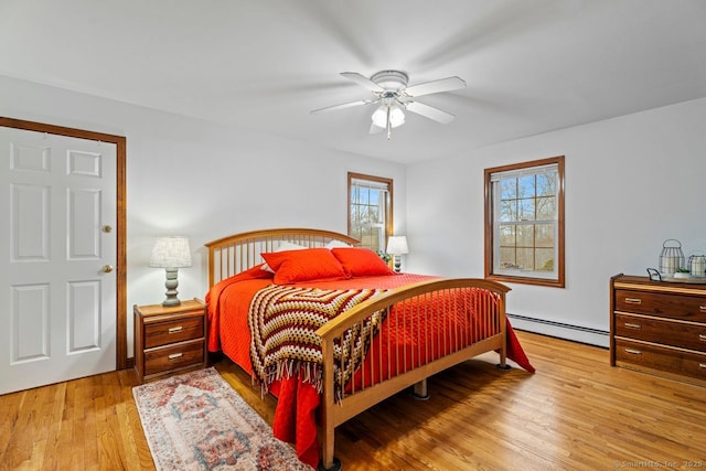 bedroom featuring a baseboard heating unit, a ceiling fan, and wood finished floors