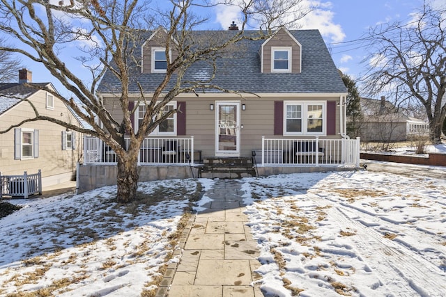 cape cod-style house featuring covered porch and roof with shingles