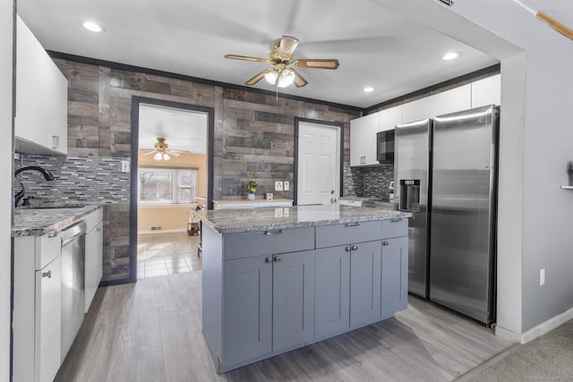 kitchen with appliances with stainless steel finishes, a sink, light stone counters, and white cabinets