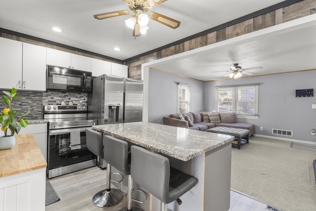 kitchen with open floor plan, appliances with stainless steel finishes, white cabinetry, and a center island