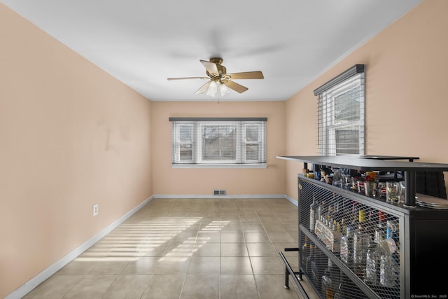 interior space featuring a ceiling fan, plenty of natural light, visible vents, and baseboards