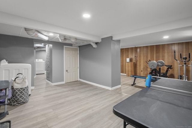 interior space featuring light wood finished floors, baseboards, wooden walls, and washer / clothes dryer