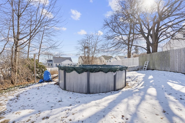 yard covered in snow with fence and a covered pool