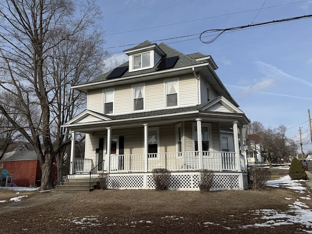 traditional style home featuring covered porch and roof with shingles