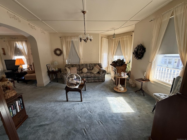 living room with arched walkways, carpet, and a chandelier