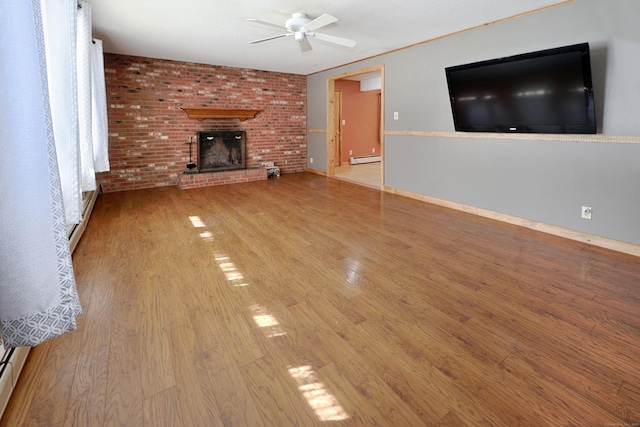 unfurnished living room featuring light wood-type flooring, baseboard heating, a fireplace, and a ceiling fan