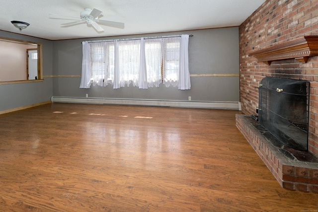 unfurnished living room with wood finished floors, a ceiling fan, baseboards, baseboard heating, and a brick fireplace