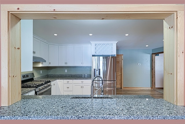 kitchen with appliances with stainless steel finishes, stone counters, and white cabinets