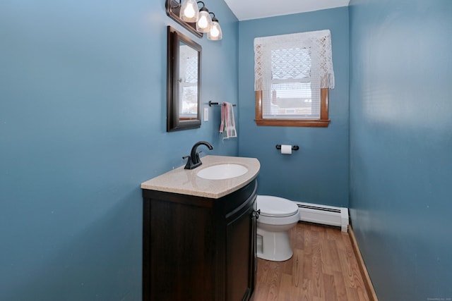 bathroom with toilet, wood finished floors, vanity, baseboards, and baseboard heating