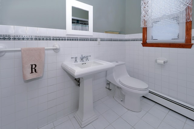 bathroom featuring a baseboard heating unit, tile patterned flooring, a wainscoted wall, and toilet