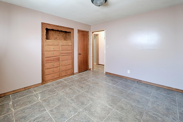 unfurnished bedroom featuring a textured ceiling and baseboards