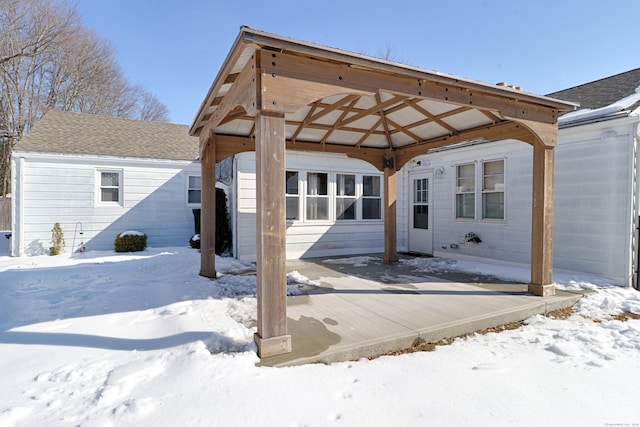 snow covered rear of property featuring a carport