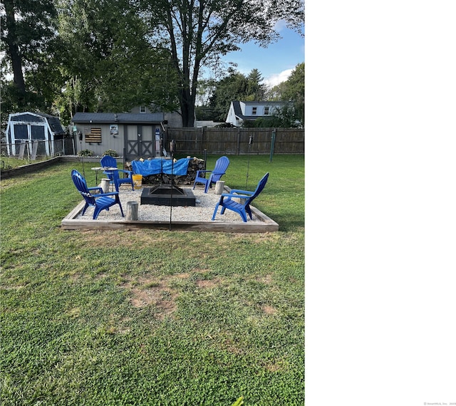 view of yard featuring a fire pit, a fenced backyard, a storage unit, an outdoor structure, and a patio area