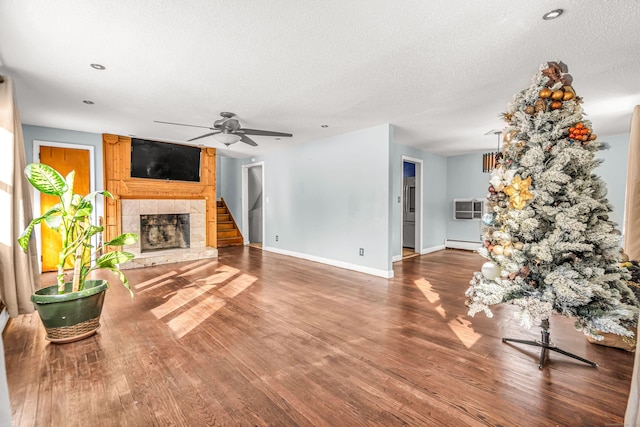 unfurnished living room featuring a textured ceiling, a baseboard radiator, a fireplace, wood finished floors, and baseboards