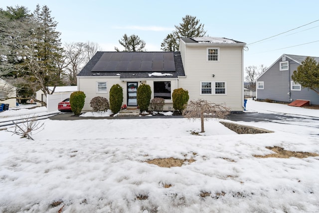 snow covered house featuring a detached garage and solar panels