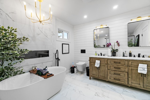 full bathroom with marble finish floor, double vanity, a freestanding bath, toilet, and a sink