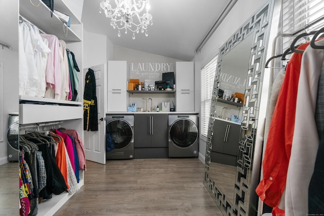 laundry room featuring a notable chandelier, washing machine and clothes dryer, a sink, wood finished floors, and laundry area