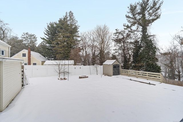 yard covered in snow featuring a storage shed, an outbuilding, and a fenced backyard