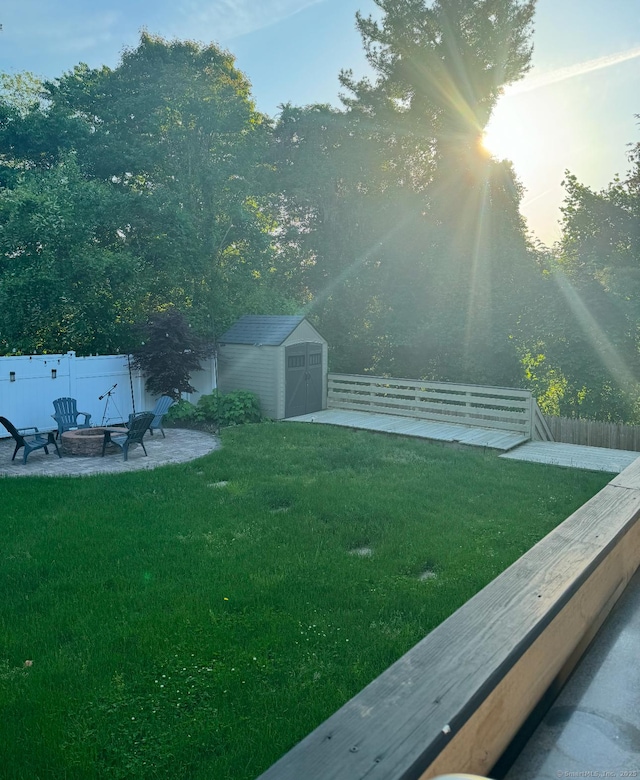 view of yard featuring a fire pit, a storage unit, an outdoor structure, and a fenced backyard