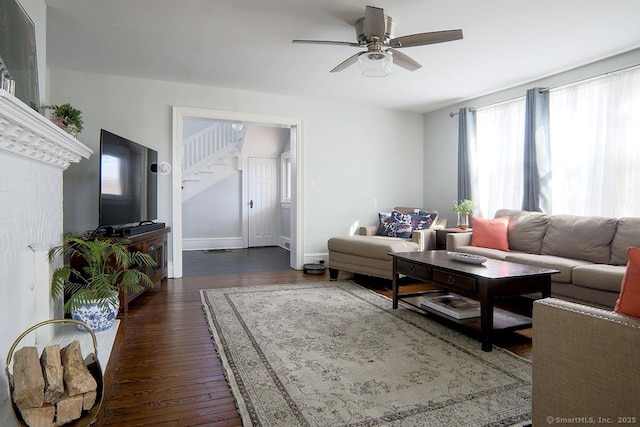 living area with stairs, ceiling fan, dark wood finished floors, and baseboards