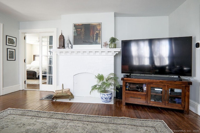 living room with hardwood / wood-style floors, a brick fireplace, and baseboards