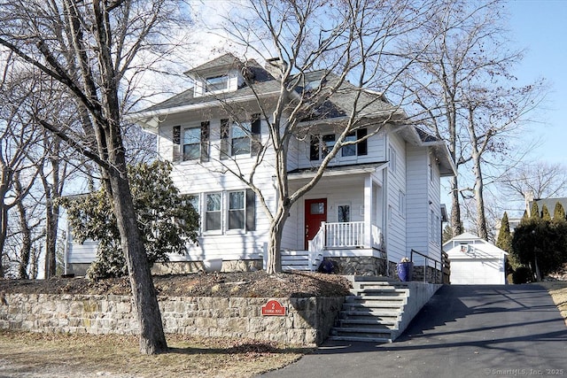 american foursquare style home featuring an outbuilding, driveway, a porch, and a garage