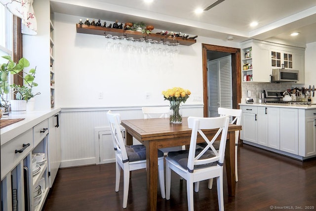 dining space with dark wood-type flooring, wainscoting, and recessed lighting