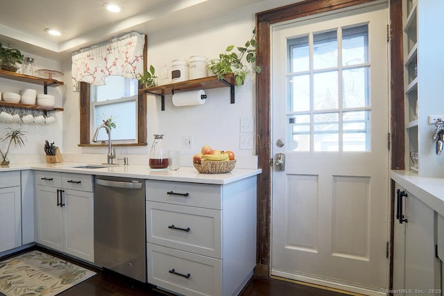 kitchen featuring light countertops, dishwasher, a sink, and open shelves