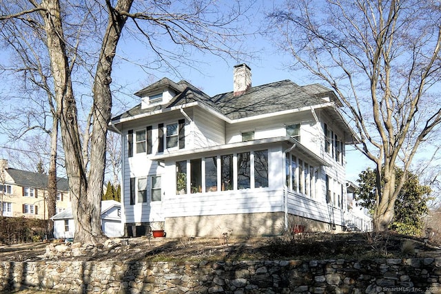 view of side of property with a sunroom and a chimney