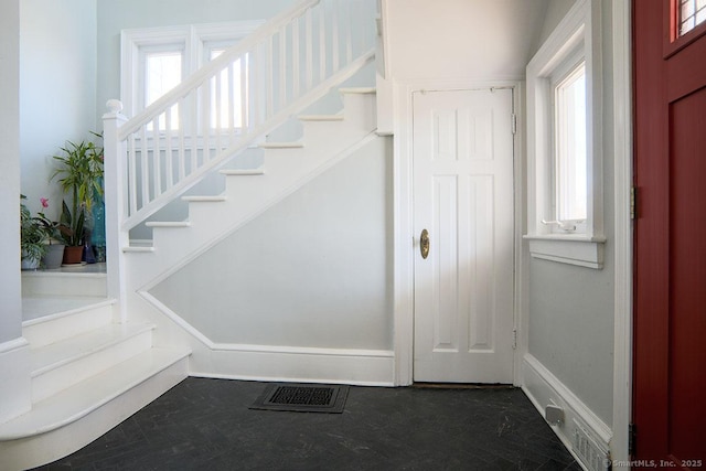 foyer entrance with visible vents, stairs, and baseboards