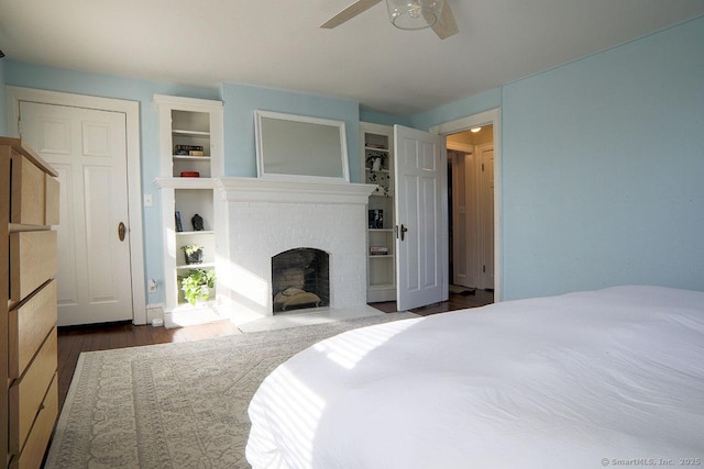 bedroom featuring a fireplace, wood finished floors, and a ceiling fan