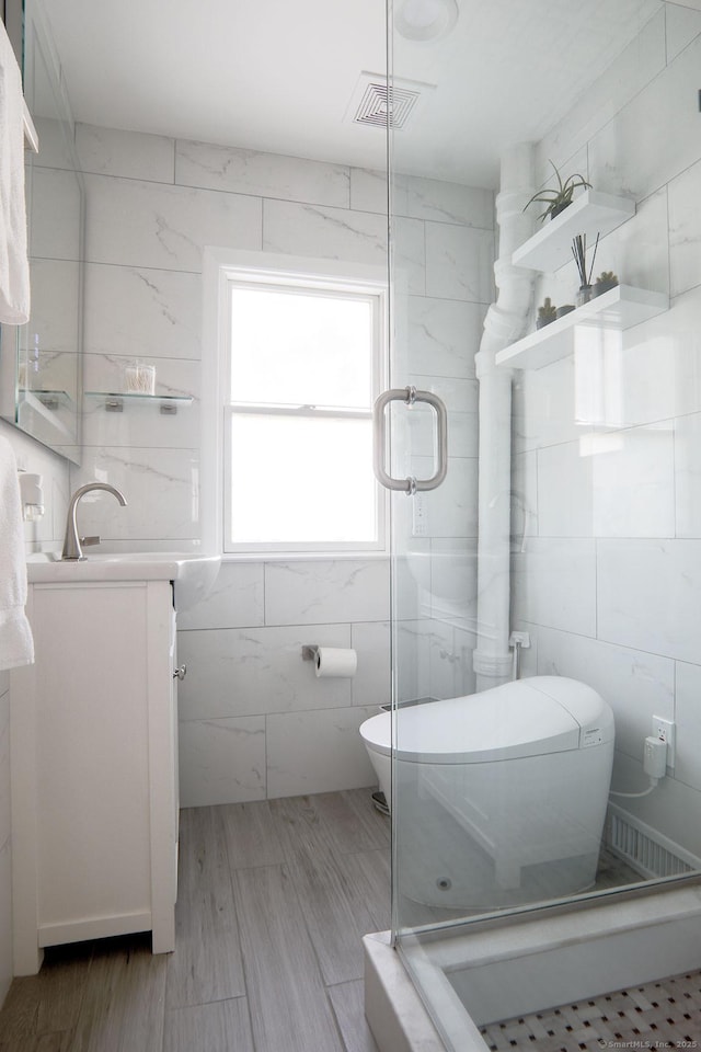 full bath with tile walls, visible vents, toilet, a stall shower, and vanity