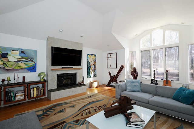 living area with lofted ceiling, a large fireplace, and wood finished floors