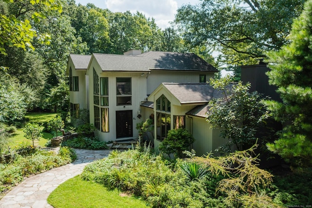 view of front of house with a shingled roof and a chimney