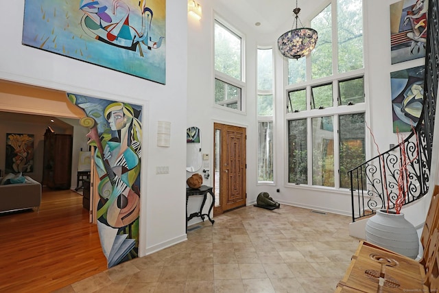 foyer entrance with a wealth of natural light, visible vents, a high ceiling, and stairs