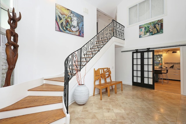 staircase featuring french doors, a towering ceiling, and baseboards