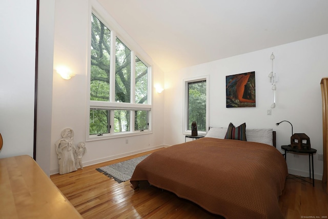 bedroom featuring vaulted ceiling, wood finished floors, and baseboards