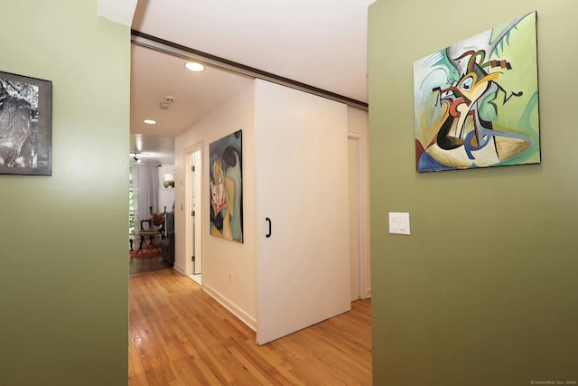 hall featuring baseboards, light wood finished floors, and recessed lighting