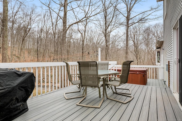 deck with outdoor dining area, a hot tub, and area for grilling