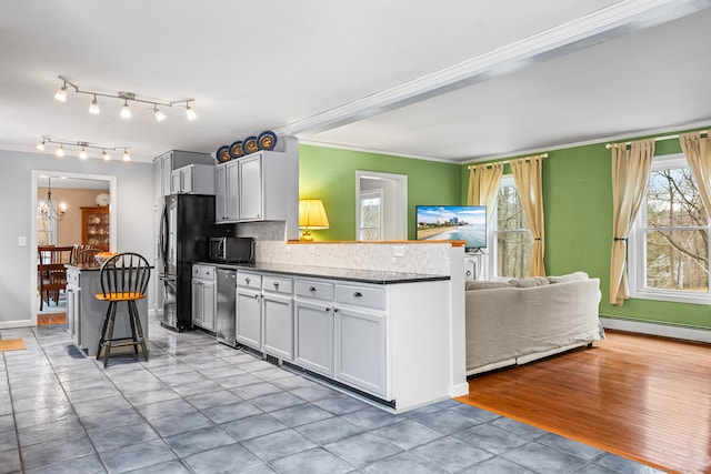 kitchen featuring a baseboard radiator, stainless steel microwave, decorative backsplash, a peninsula, and a kitchen breakfast bar